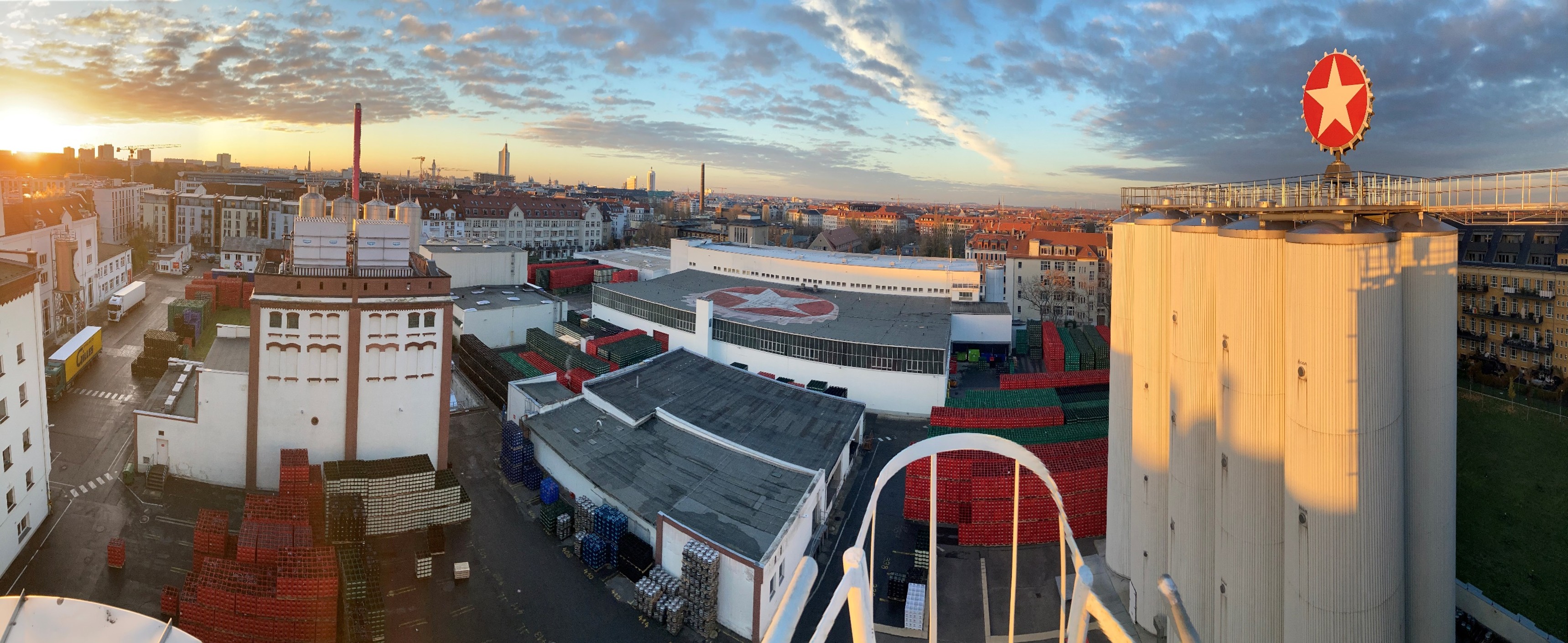 The Sternburg brewery with a view over Leipzig in the background. The sun is setting on the horizon.
